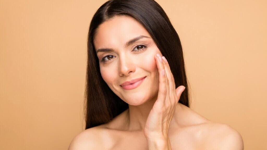 Beautiful, Young Woman Touching her skin in Hastings, NE & Grand Island, NE | Essence Medspa